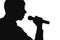 Silhouette of a man singing into a microphon