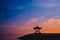 Silhouette of a man sitting in a gazebo on the beach at dawn on Sanur beach, Bali, Indonesia. A man admires the dawn