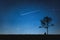 Silhouette of man sitting on mountain and night sky with shooting star. Alone concept