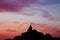 Silhouette of a man sitting on a rock during sunset.