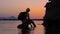 Silhouette of a man sitting on the stone with seascape on background. Adult tourist sitting on the stone with legs in