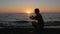 Silhouette man with smartwatch on hand at sunset beach. He touches the smart watches and checks the message. The sun is