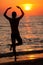 Silhouette of man standing backwards at sea water edge and enjoying sunset