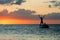 Silhouette of man standing in a boat on the background of sunset