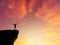 Silhouette man standing on mountain cliff sunset background