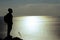 Silhouette of man standing on a rock and looking at sea
