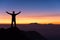 silhouette of man standing and spread hand on the top of mountain to enjoy colourful sky.