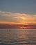 The silhouette of a man standing on a surf board on the sea as the sun sets over the nuclear power plant BarsebÃ¤ck seen in the