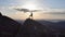 The silhouette of a man standing triumphantly on a mountain top at sunset.