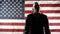 Silhouette of a man in a suit gesticulating and speaking against the background of the American flag