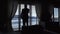 Silhouette of a man talking on cell phone while standing in a hotel room by the window with blinds