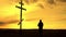 Silhouette man on top of the mountain looking with hope at the Christian Cross. A man making a confession to the cross, background