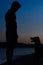 Silhouette of man training his dog on the beach