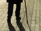 Silhouette of man walking with a cane, long shadow on pavement