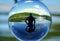 A silhouette of a man in the water at a lake, captured through a crystal lens ball