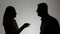 Silhouette of a man and a woman. A family quarrel, a man and a woman shout at each other emotionally gesticulating with