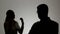 Silhouette of a man and a woman. Family quarrel, the woman shouts at the man and emotionally gesticulating hands,