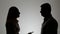 Silhouette of a man and a woman. Family quarrel, the woman shouts at the man and emotionally gesticulating hands,