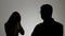 Silhouette of a man and a woman. Family quarrel, the woman shouts at the man and emotionally gesticulating hands,