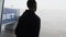 Silhouette of a Masked Young Man at Airport Terminal Window Looking at Planes