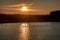 Silhouette of men on sup board with oar in hands on lake in evening with magnificent sunset in background