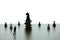 Silhouette miniature businessman standing in front chess piece at coin stack