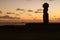 Silhouette of a Moai at Ahu Tahai against sunset sky and Pacific ocean, Archaeological site on Easter Island, Chile