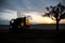 Silhouette of mobile air defence truck with radar antenna during sunset. Satellite dishes or radio antennas against evening sky