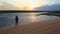 Silhouette Mother Carries Small Girl on Dunes at Dusk by Lake