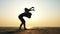 Silhouette of mother with daughter doing gymnastic on the beach at sunset