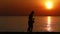 silhouette of mother doing exercises to kid on beach at sunrise