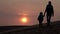 Silhouette of mother holding her baby child hand and going away from camera