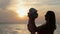 Silhouette of mother kissing baby at sunset near
