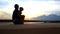 Silhouette Mother Sits Carries Small Girl by Lake at Dusk