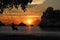 Silhouette of mother and son sitting on cradle or hammock on the beach with red sky sunset