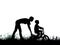 silhouette of a mother who teaches his son to ride a bike