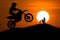 Silhouette of Motorbike rider jump cross slope of mountain with