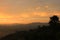 Silhouette of mountain and big tree with sunlight, clouds and orange sky background in the early morning