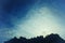 Silhouette of mountain ridge with bare tree - artistic image with glowing fade filter