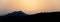 Silhouette of mountains as dusk falls with the sun in the background