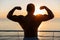 Silhouette of muscular showing biceps at sunnrise