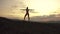 Silhouette of muscular woman fitness instructor with perfect body stretching outdoor on sunset. Cloudy sky