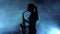 Silhouette musician female playing on saxophone. Smoky studio, slow motion