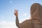 Silhouette of muslim woman in head scarf launching a paper airplane on blue sunset sky background. Travel concept.