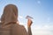 Silhouette of muslim woman in head scarf launching a paper airplane on blue sunset sky background. Travel concept.