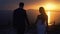 Silhouette of newlyweds walking on background of sunset on ocean, slow motion