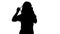 Silhouette A nice young woman straightens her hair looking in th