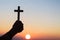 Silhouette off hands holding wooden cross on sunrise background, Crucifix, Symbol of Faith