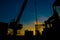 Silhouette of oil and gas wellhead platform and well service worker while working to perforation gas and crude oil reservoir.