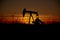 Silhouette of oil pump operation at drilling site against vibrant sunset backdrop